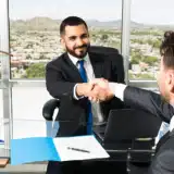 Le patron serre la main d’un nouvel employé en souriant.