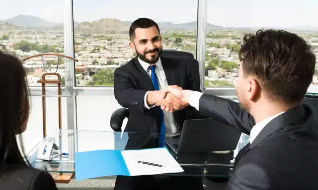Le patron serre la main d’un nouvel employé en souriant.